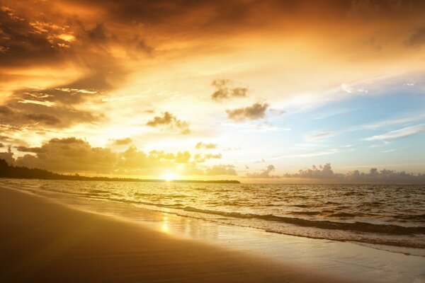 Von der Morgensonne überflutete Meereslandschaft mit Sand, Meer und Wolken