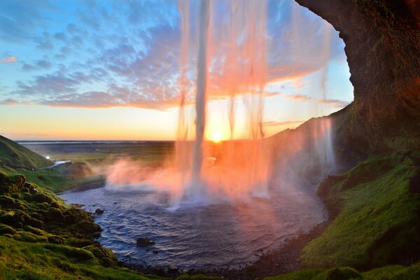 Caída de la cascada en el fondo de la puesta de sol. Islandia
