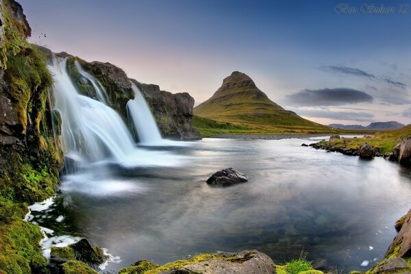 Bergwasserfälle in Island vor dem Hintergrund eines Vulkans und eines Sees