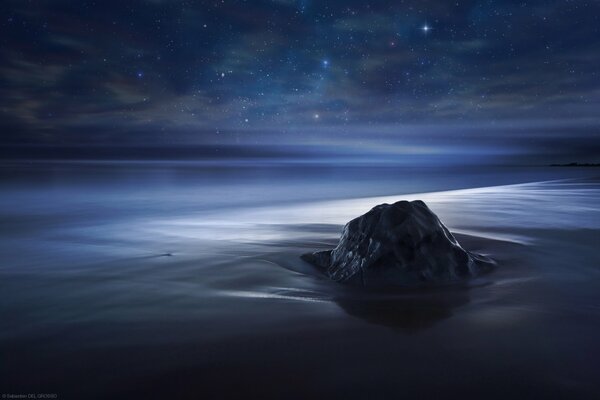 Roca de olinokaya contra el océano y las estrellas