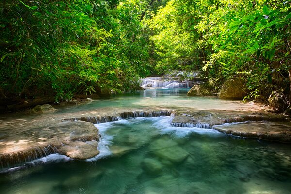 Ein Fluss in Thailand unter Laub mit einem kleinen Wasserfall