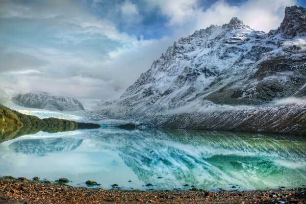 Transparenter Bergsee, schneebedeckte Felsen