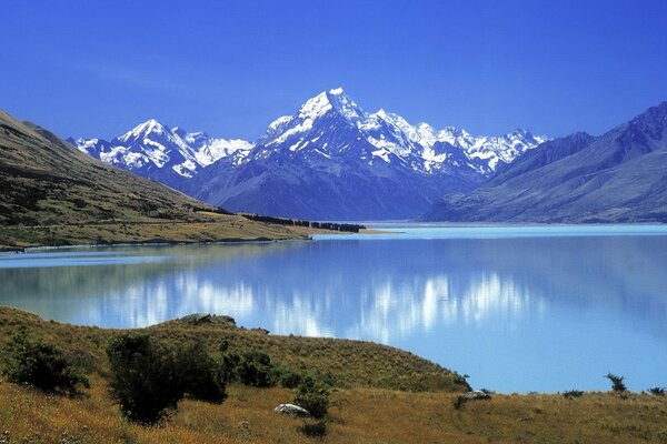 Altas montañas con copas de nieve y con hermosas vistas del lago al pie y la naturaleza