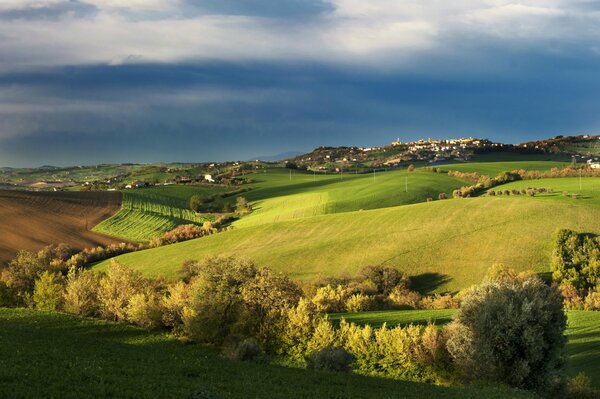 The autumn field of Tuscany, in the distance clouds bent low over the village