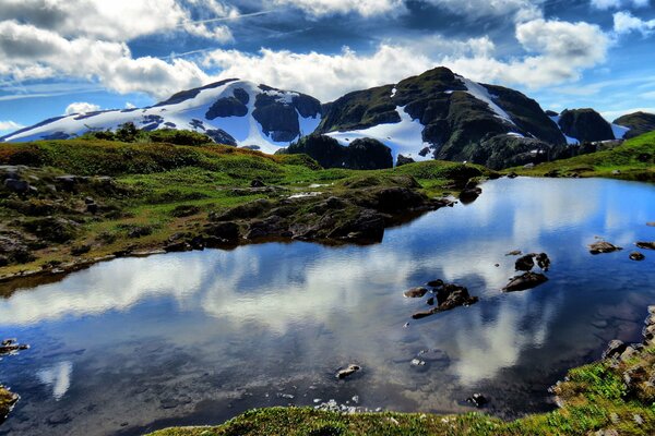 Le nuvole si riflettono nel lago ai piedi delle montagne