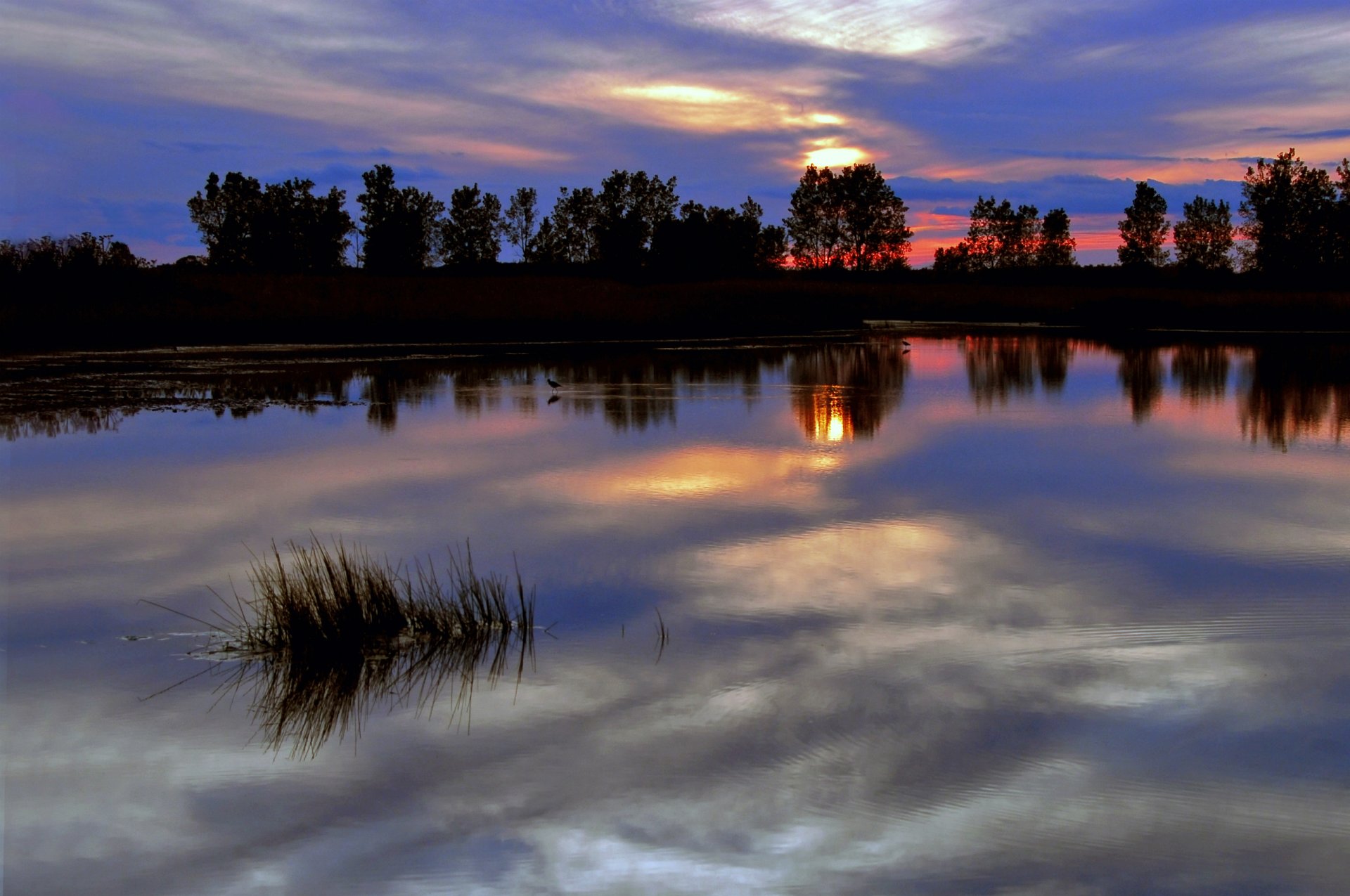 sera crepuscolo luminoso rosso tramonto cielo nuvole blu alberi fiume superficie liscia riflessione