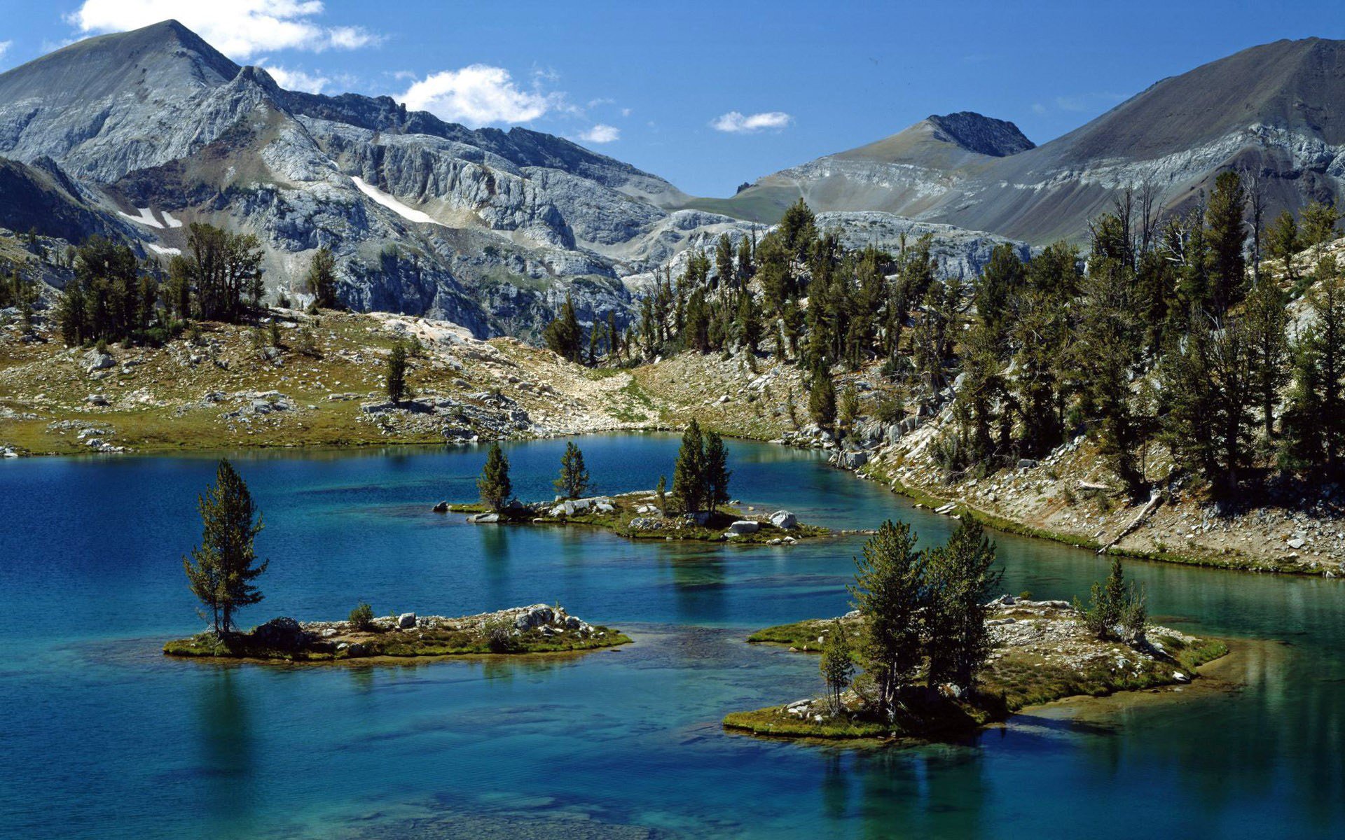 roches montagnes sommets pente forêt arbres rivière lit îlots courant îles ciel nuages