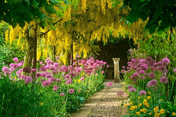 An alley of flowers and yellow trees leading to the column
