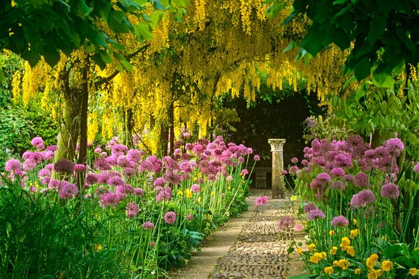 Vicolo di fiori e alberi gialli che conduce alla colonna