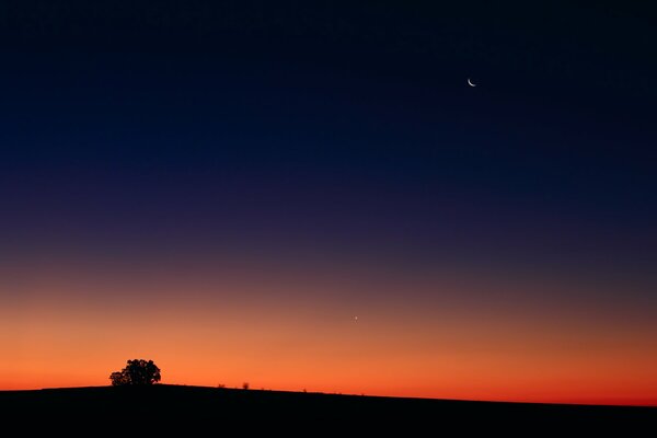 Coucher de soleil rouge. Lune dans le ciel nocturne