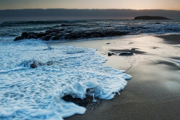 Olas de espuma bañan la arena