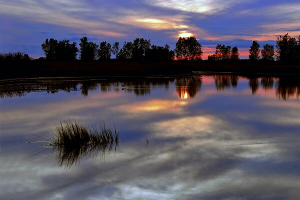 La calma superficie del fiume serale che riflette il cielo