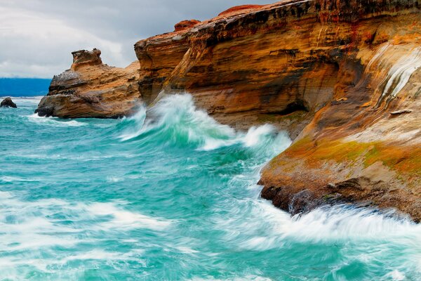 Onde azzurre che battono contro le rocce rosse