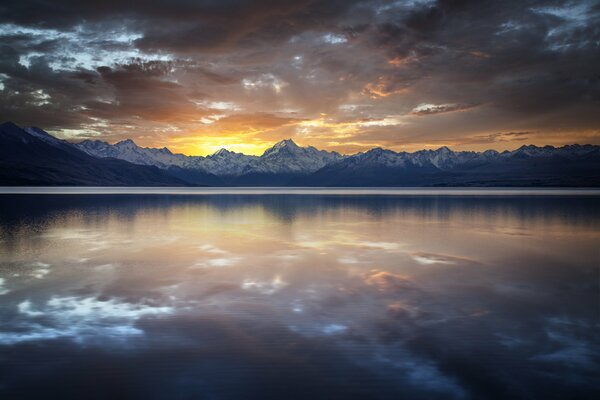 Reflection of clouds in the lake against the background of snow-capped peaks