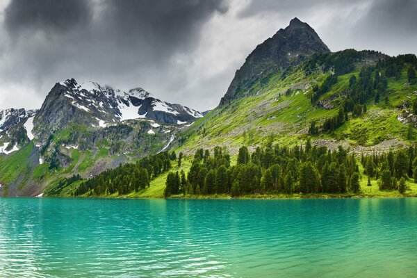 Чистое голубое озеро среди заснеженных гор