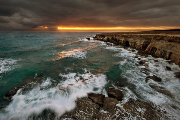 Puesta de sol en la costa rocosa del mar