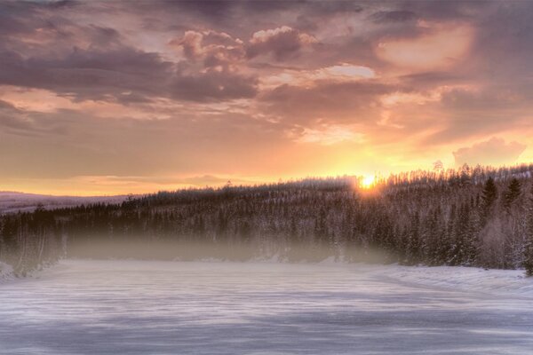 Coucher de soleil et rivière gelée couverte de brouillard