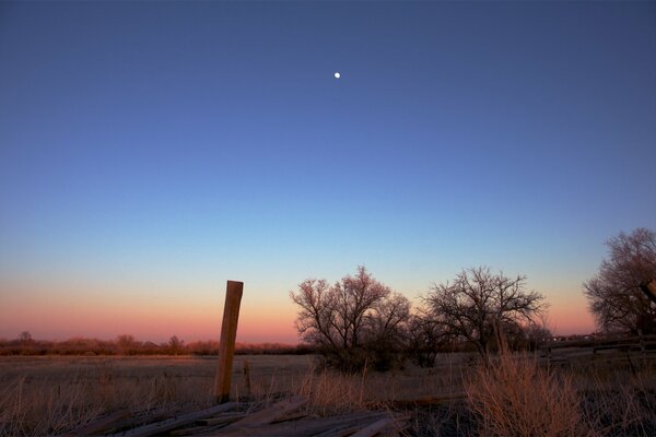 Вечерний закат в поле и луна на небе