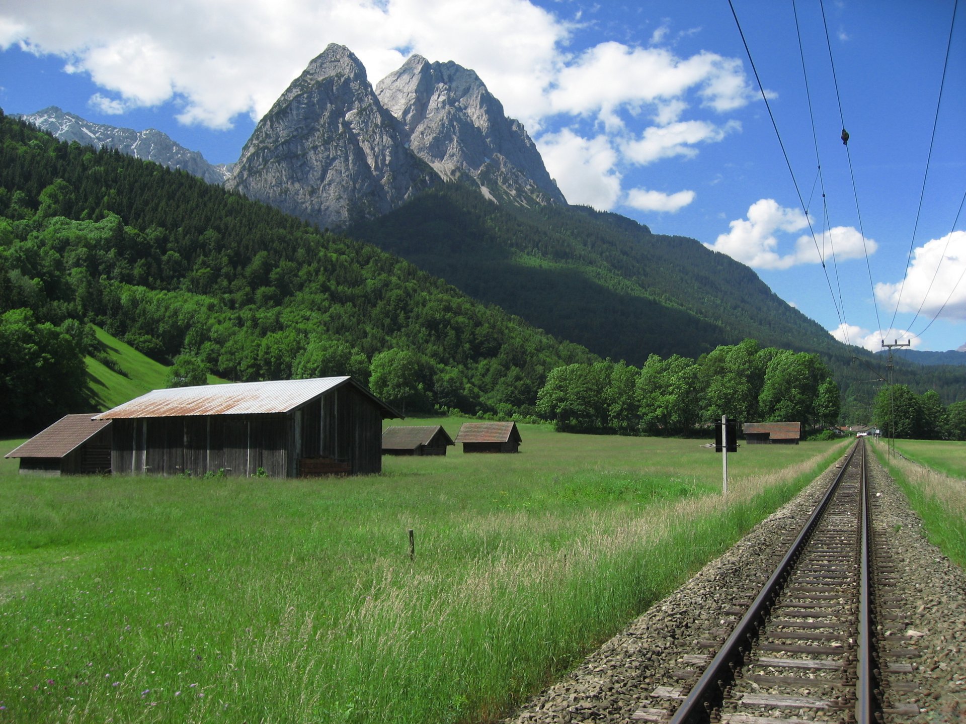 ferrovia rotaie fili montagne valle cielo nuvole natura foto cima picco montagna paesaggio case radura erba foresta alberi