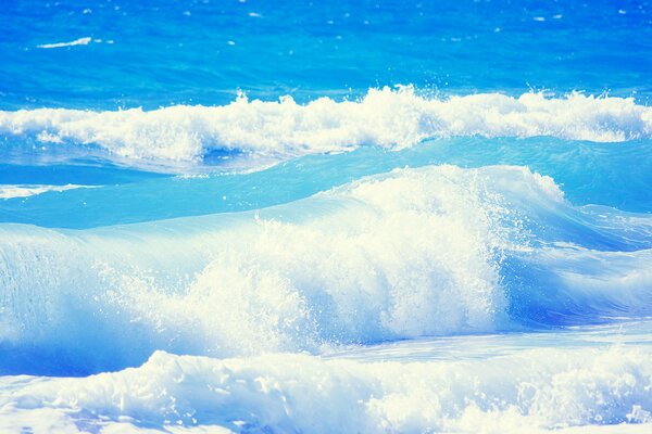 The waves of the blue ocean break on the shore