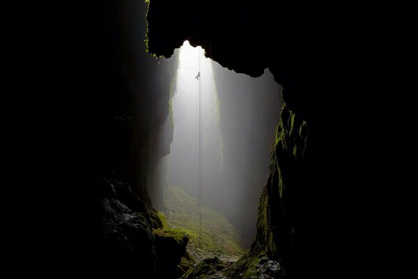 Corde descendue dans une grotte envahie par la mousse