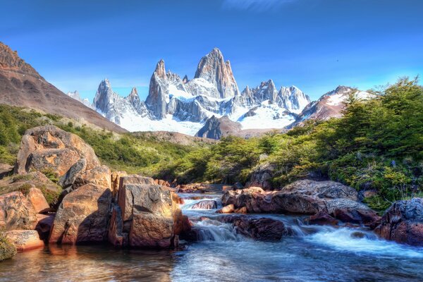 Montañas cubiertas de nieve con cascada y piedras