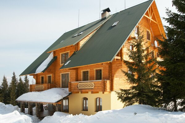 Zweistöckiges Cottage in einer Schneedecke unter Tannen