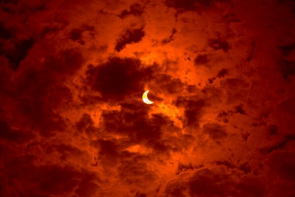 Partial solar eclipse in red clouds