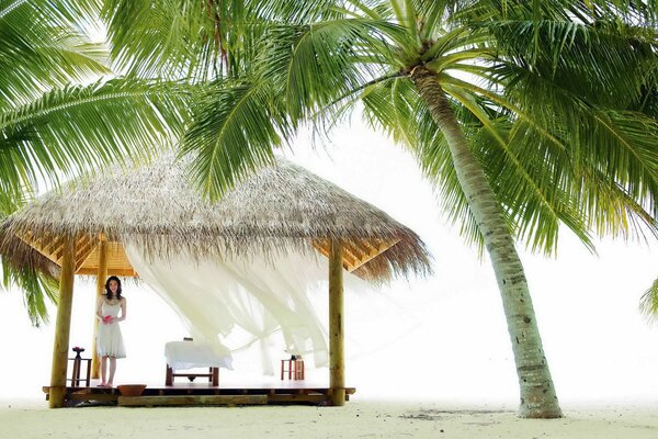 Resting girl on the beach by the palm trees