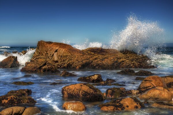 Wellen an Steinen im Meer spritzen