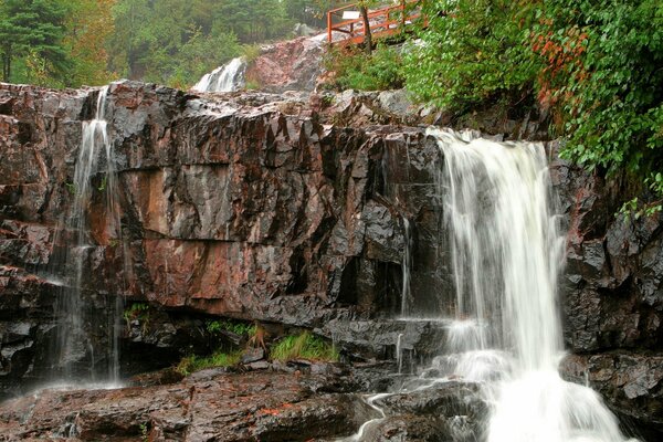 Eine Brücke zwischen Felsen, riesigen Steinblöcken am Wasserfall