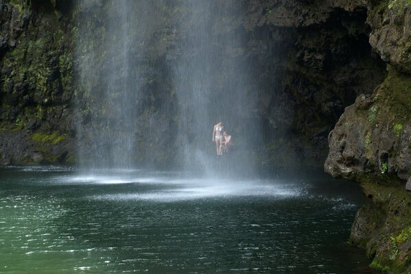 Das Paar sitzt unter einem Felsen und ein Wasserfall fließt in der Nähe