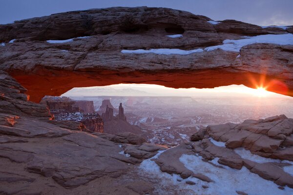 The sun is shining brightly behind the rocks