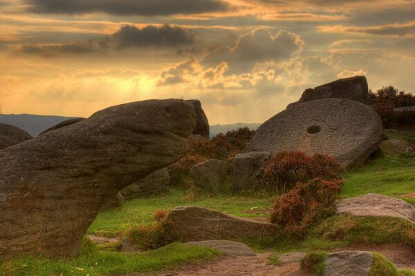 Large boulders in a green clearing under thick clouds