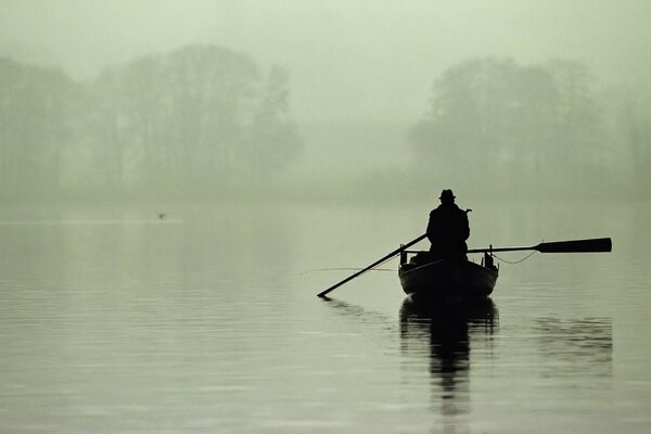 Pescador solitario en un barco en la niebla