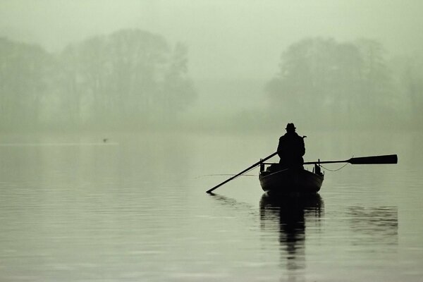 Pêcheur solitaire sur un bateau dans le brouillard