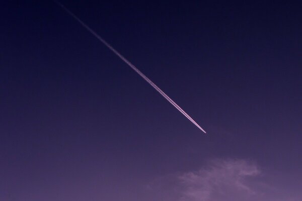 The trail of the plane in the sky in purple tones