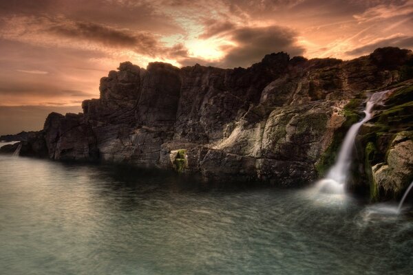 Landscape of waterfall and rocks at sunset