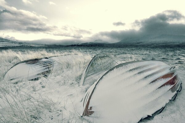 Bateaux sur la rive de la rivière en hiver sous la neige