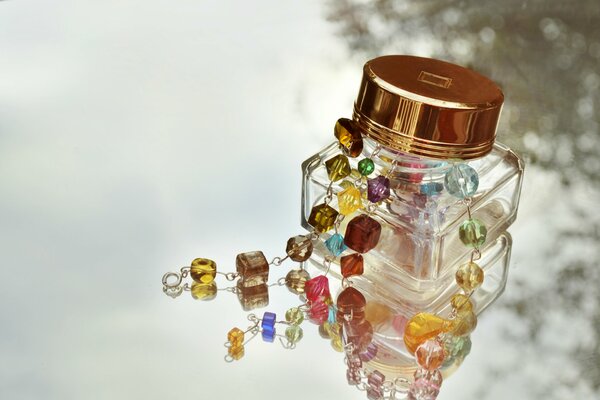 Jewelry with stones in a jar on glass