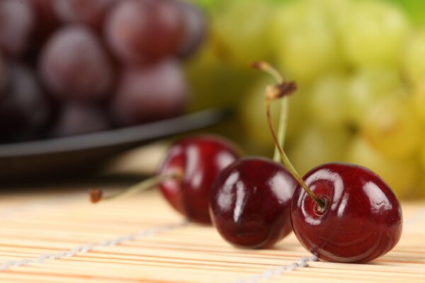 Cerezas maduras sobre el fondo de las uvas