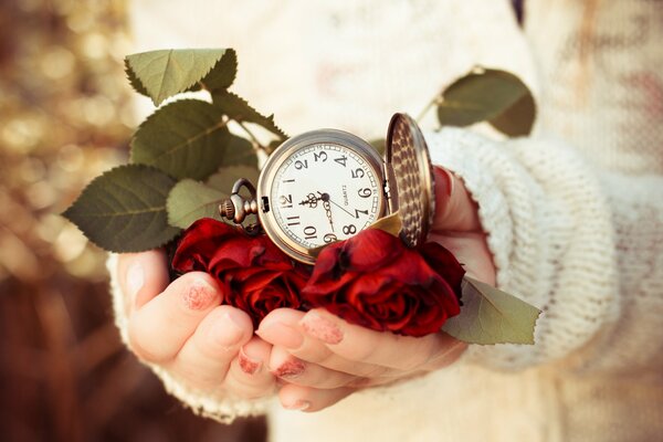 In den Händen des Mädchens ist das Zifferblatt der Uhr umgeben von roten Rosen