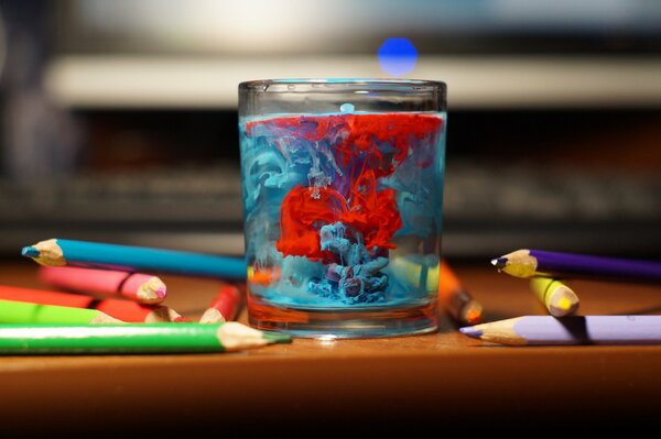 Malownicza woda w szklance i kolorowe kredki