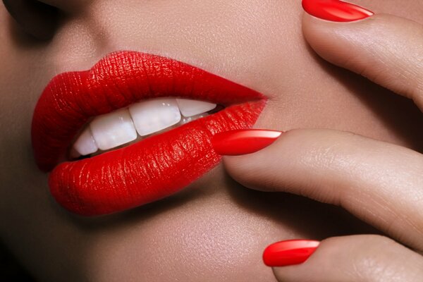 Macro photo of face and hands with red lipstick and varnish