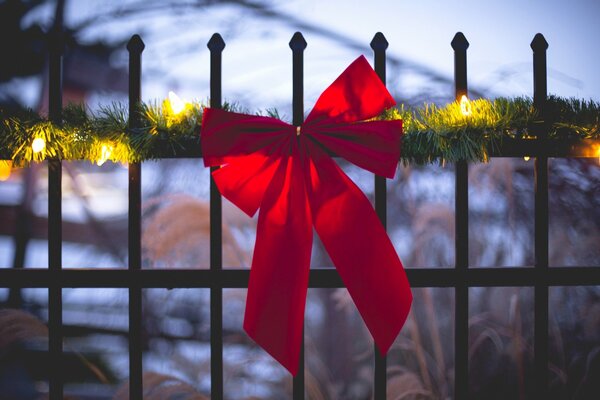 Nastro festivo rosso su un recinto decorato con una ghirlanda di conifere