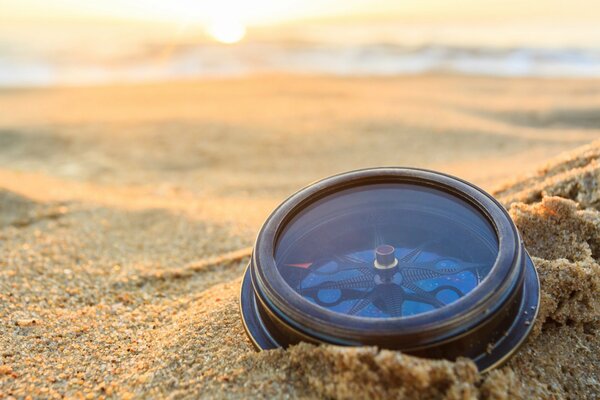 Kompass im Sand im Morgenlicht der Sonne