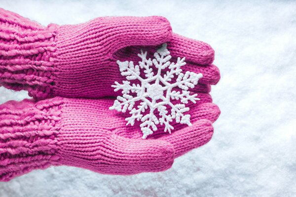 Copo de nieve en las manos con guantes rosados