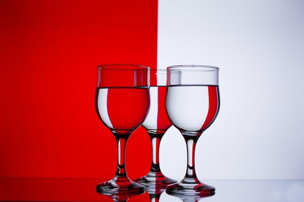 Wine glasses with water on a red and white background