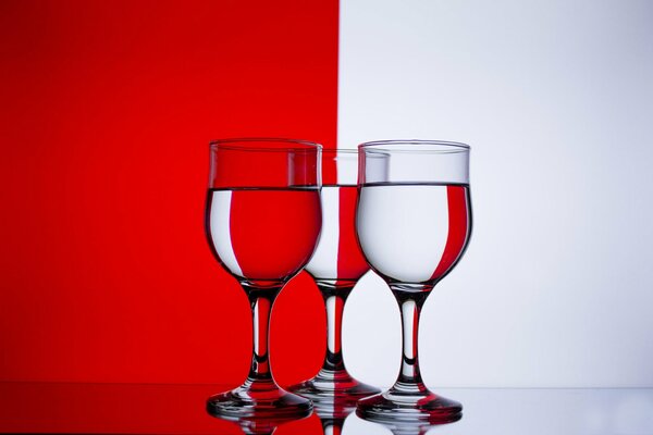 Verres à vin avec de l eau sur fond rouge et blanc