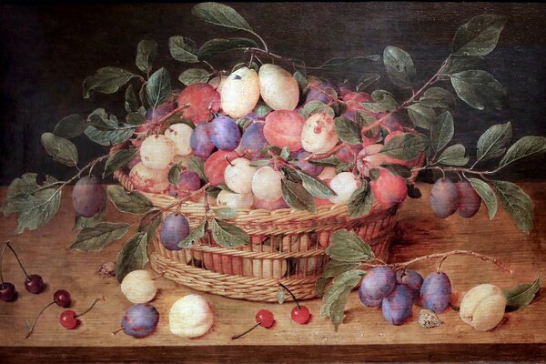 A basket with plums and cherries is on the table
